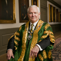 Robert Gates wears his green and gold chancellor's regalia while sitting in the hall of presidential portraits