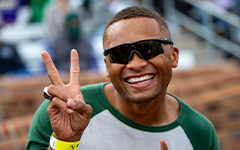 Smiling person posing with a peace sign with their fingers at a Tribe football game in Zable Stadium
