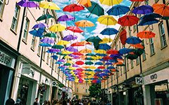 Rainbow umbrellas hang over an alley way