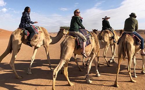 Students riding camels in the Wahiba Sands of Oman