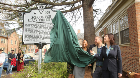 Jody L. Allen, director of the Lemon Project; Mark Kostro Ph.D. '18, senior staff archaeologist for the Colonial Williamsburg Foundation; and W&M President Katherine A. Rowe help to unveil the historical marker for the Bray School. (Photo by Stephen Salpukas)