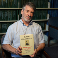 History Professor Christopher Grasso holding one of his books