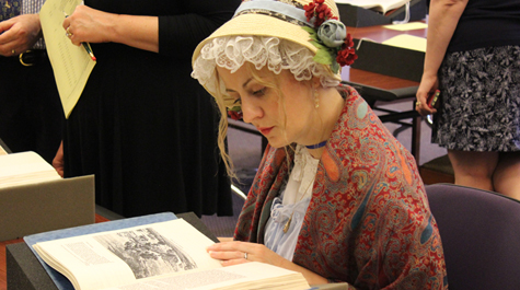 A person dressed in period clothing looks at a book