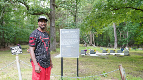 Travis Harris stands in front of gravestones at Oak Grove Cemetery