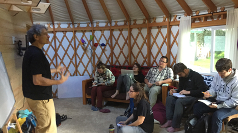 Students listen to lecture while sitting in yurt