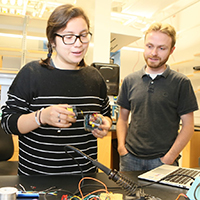 Kelly Rodriguez-Vasquez demonstrates the AIRduino device in the lab with Nathan Kidwell
