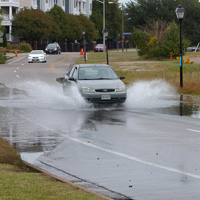 A car drives through water on a roadway