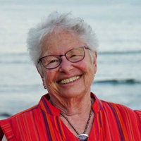 Professor Iris Anderson stands in front of a body of water and smiles at the camera