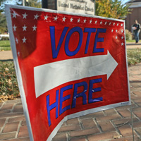 A sign saying Vote Here points down a brick pathway