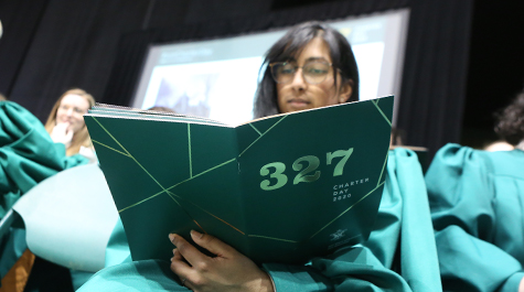 A person in a choir robe looks at a program with a green cover and 327 on it