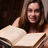 Caitlin Dolt ’22 stands beside the Swem Special Collections' copy of Isaac Newton’s “Principia.” 