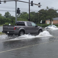 A truck drives through flooding on a roadway