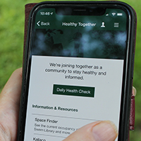 A hand holding a mobile phone and using the Healthy Together tool