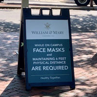 A sign on a sidewalk that says masks are required