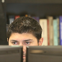 A person at a computer in front of a bookcase