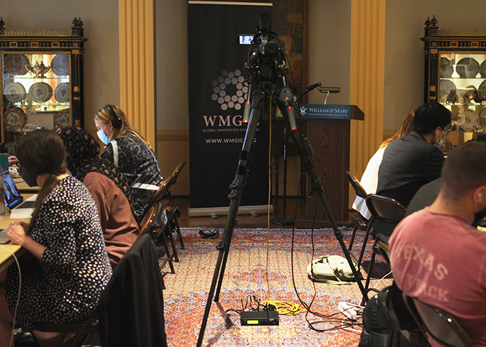 Pre-event set up in the Reves Room with a video camera and students working on laptops. (Photo by Tyler Lawrence)