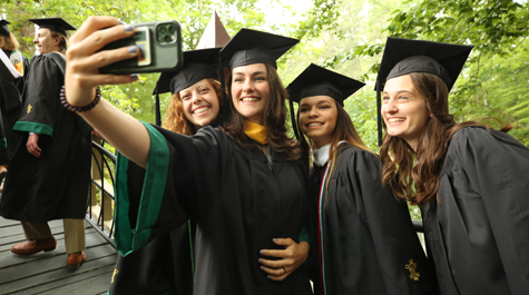 A group of people in caps and gowns takes a selfie
