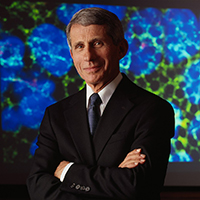 Dr. Fauci pictured in front of a microscope projection of virus