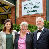 Three people stand in front of a brick building with a sign on it that says Bee McLeod Recreation Center