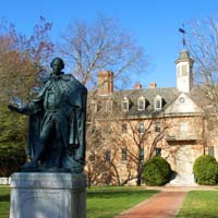 The statue of Lord Botetourt stands in front of the Wren Building on a sunny day
