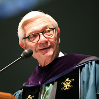 President Taylor Reveley wearing regalia stands at the podium of an event