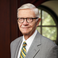 President Taylor Reveley in a suit standing in the Great Hall with window in the background