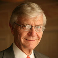 President Taylor Reveley in a suit with orange tie smiles at the camera
