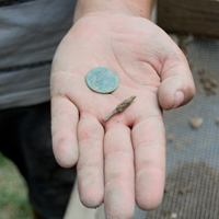 A slate pencil fragment, one of 40-some found at the site, came out of the sifter along with a bonus find—a 1773 British coin. (photo by Joseph McClain)