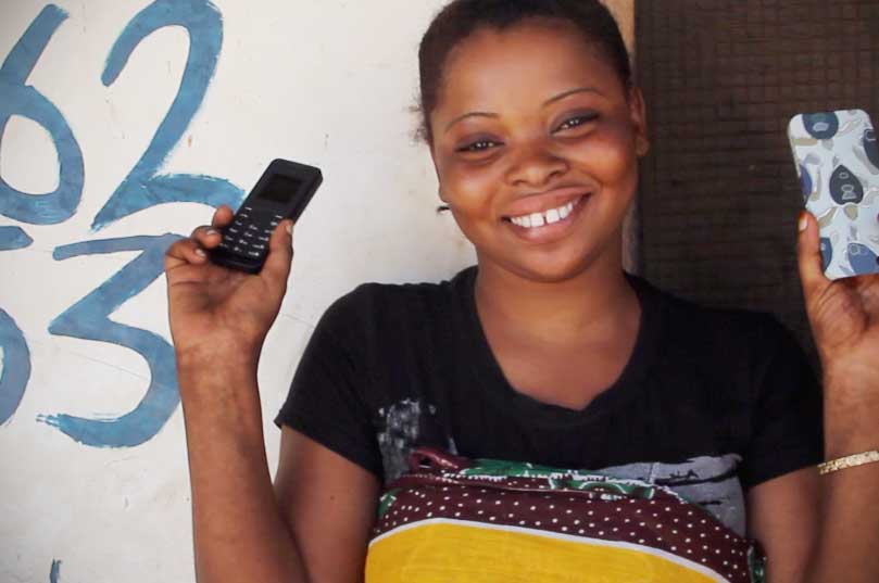 A Tanzanian woman holding a phone she received from Kidogo-Kidogo and a Kidogo iPhone case
