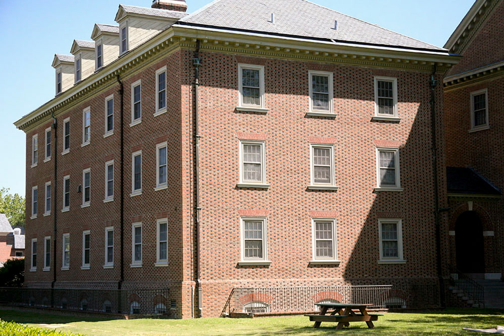 A corner view of a brick, windowed dorm building.