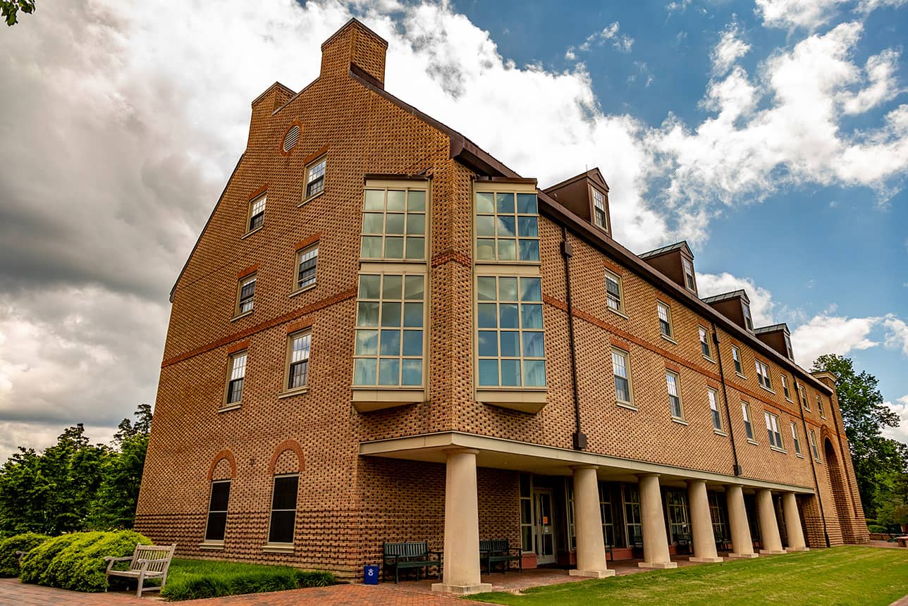 Three story brick residence hall with large windows and entrances on the ground level