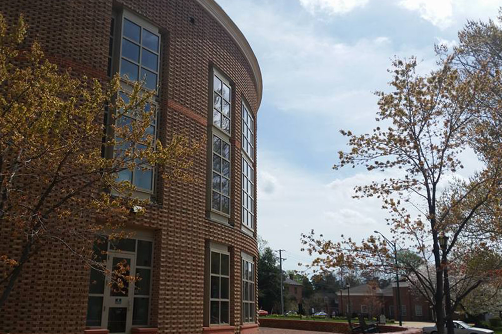 Brick dorm building with a large, windowed space and patio.