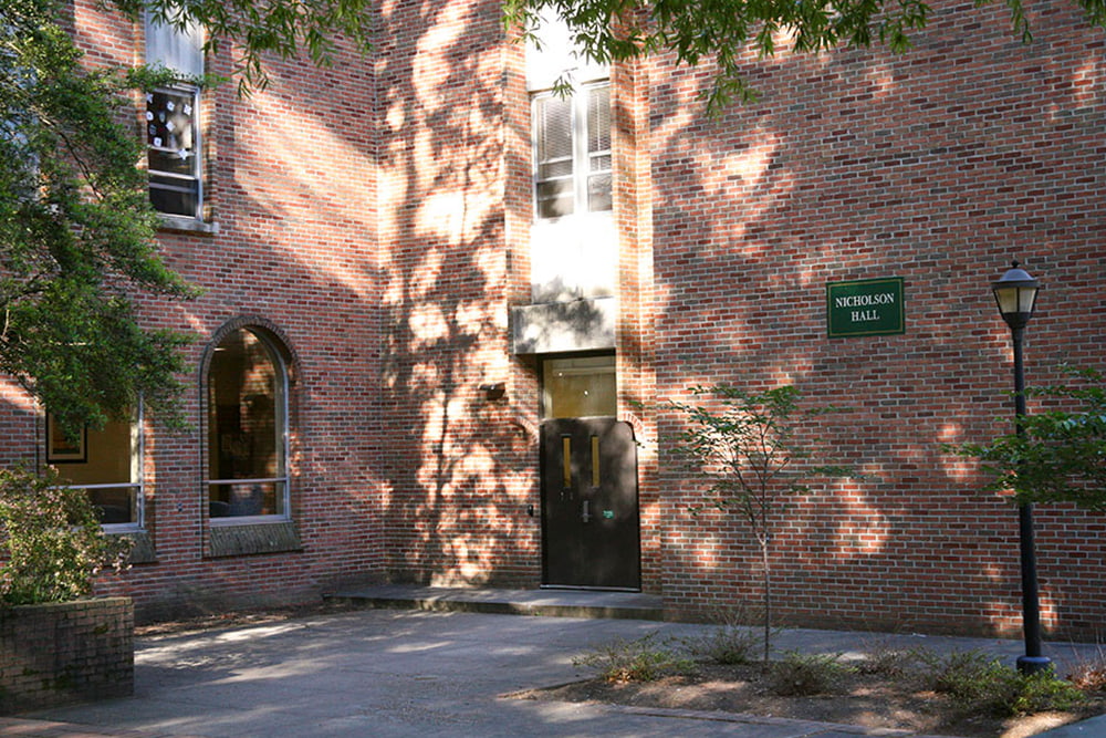 The entrance and two arched windows of a bricked dorm building.