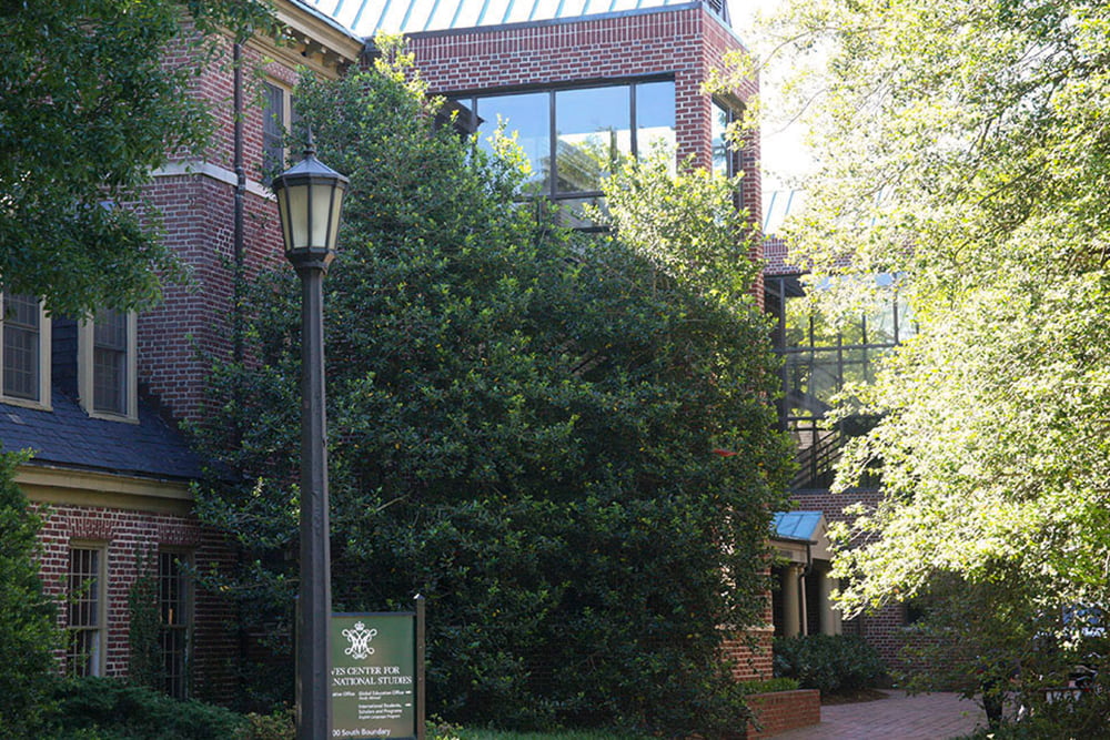 Brick dorm building with a large, windowed space nestled in greenery.