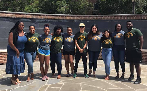 PLUS counselors wear William & Mary t-shirts in front of a giant chalkboard.