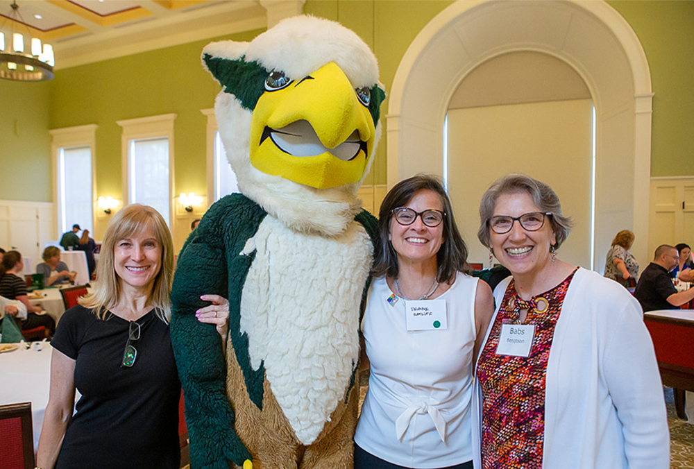 Three William & Mary employees pose with the university mascot.