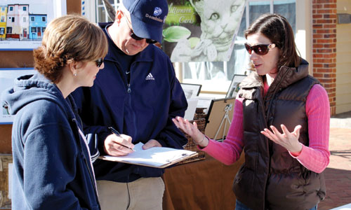 Katie Moriarty, an M.B.A. student at the Mason School of Business at the College of William & Mary, discusses the idea of a community-supported fishery with a pair of festival-goers during the 2nd Sundays Williamsburg Arts and Music Festival in March