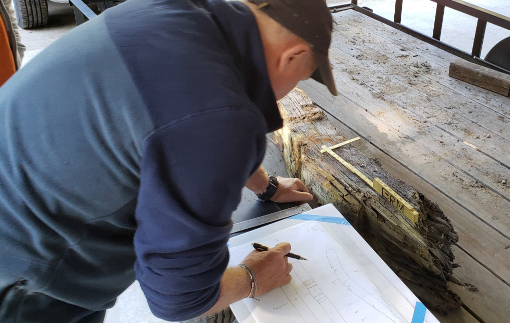 Maritime archaeologist preparing measured drawing of a ship's timber.