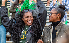 Two people cheer and smile at a Tribe football game in Zable Stadium