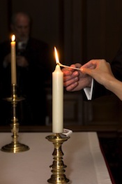 The Wren Building's brass unity candlestick lit by six-inch wick tapers.