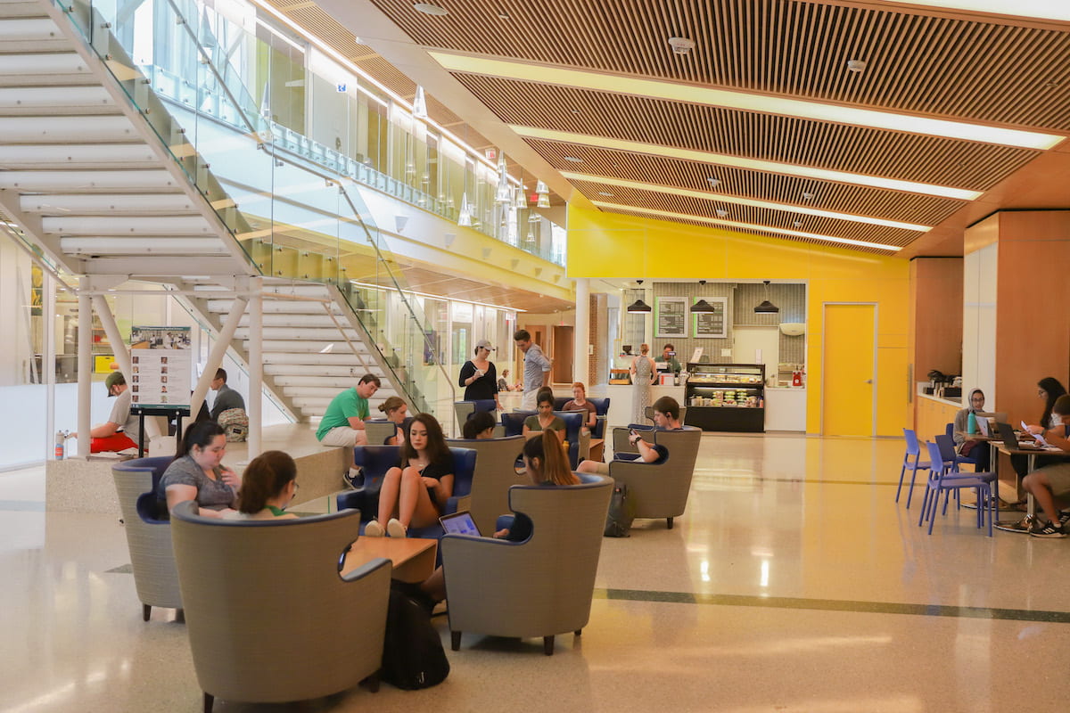 Students studying and eating in the brightly lit modern atrium of the ISC by a coffee shop counter