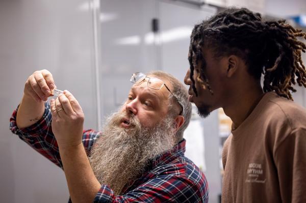 Professor holding up test tube with student examining alongside him