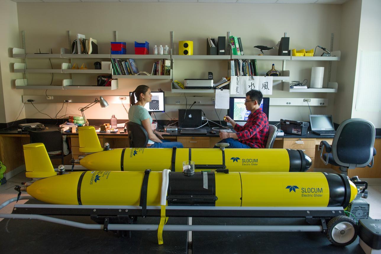 students working at desks in lab surrounded by equipment