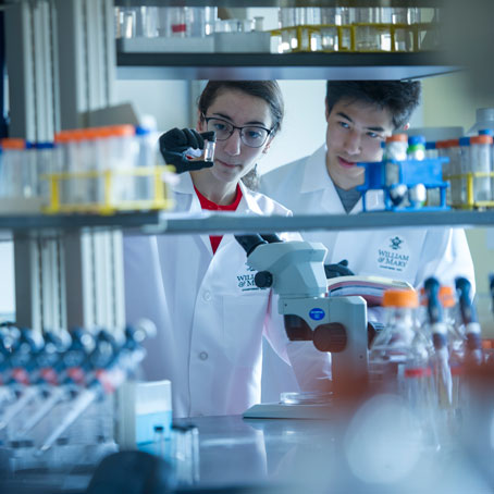 Two students in lab coats working in a lab