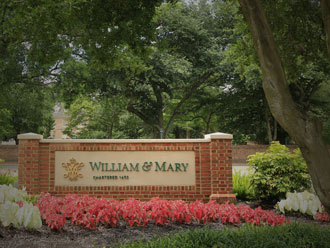 Brick William &amp; Mary sign surrounded by flowers and green trees