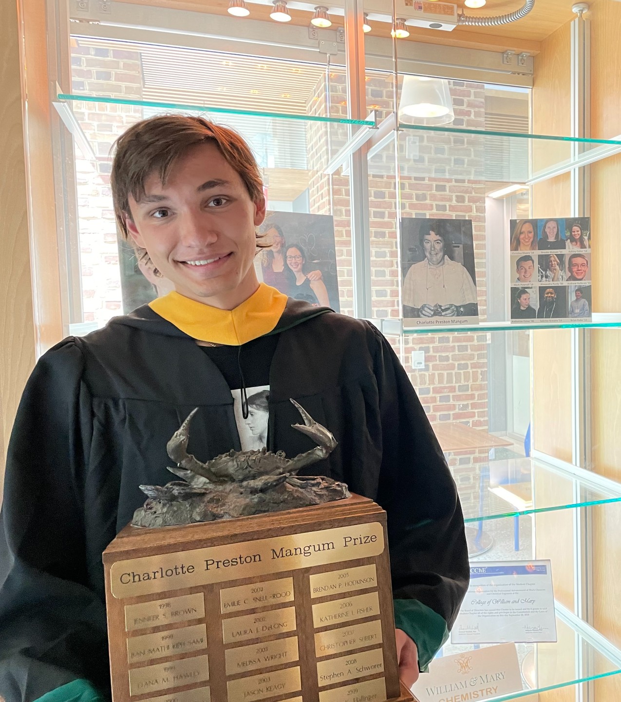 Augustin Kalytiak-Davis ’22 poses in front of the display case where his name has been added to the list of winners on the Charlotte Preston Mangum Prize