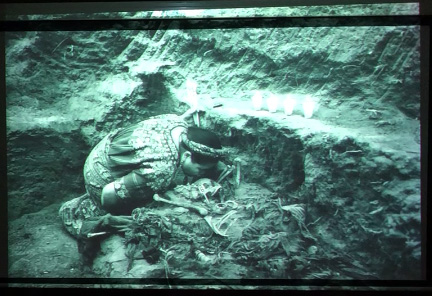 Slide 13: A woman, kneeling. She is kissing a skeleton that is partially exhumed from a mass grave.