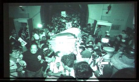 Slide 2: A large group carrying a coffin.