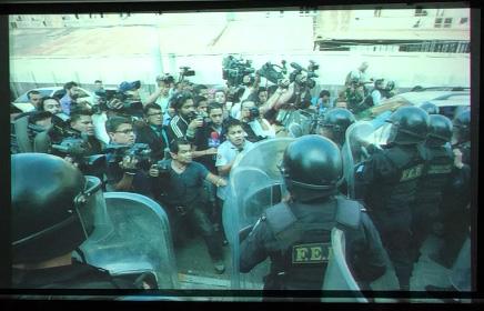 Slide 23: Police clashing with a group of civilians, journalist video cameras held overhead.