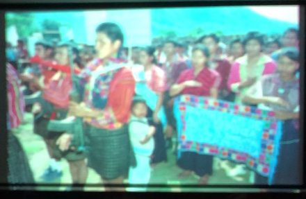 Slide 5: A group of civilians, wearing brightly colored clothes, carrying a sign.